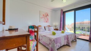 Une chambre à coucher avec un lit, un bureau et une chaise. Il y a une fenêtre qui donne sur les bâtiments à l’extérieur.
