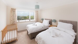 Une chambre d’hôtel avec deux lits, un berceau et une vue sur la campagne.