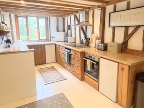 A modern kitchen with wooden cabinetry, a built-in oven, a microwave, and a bread box.