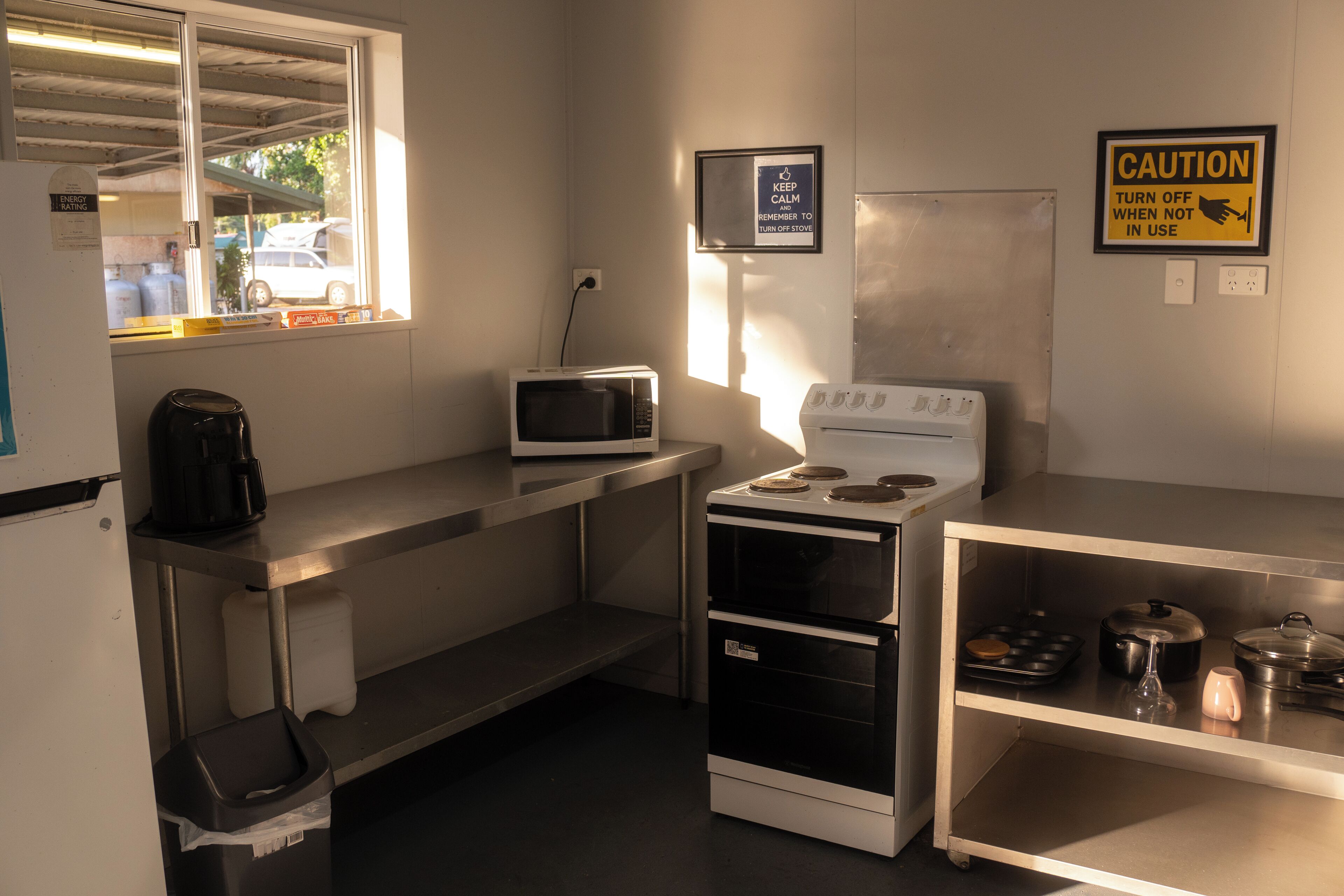 A compact kitchen with a microwave, stove, and a caution sign.