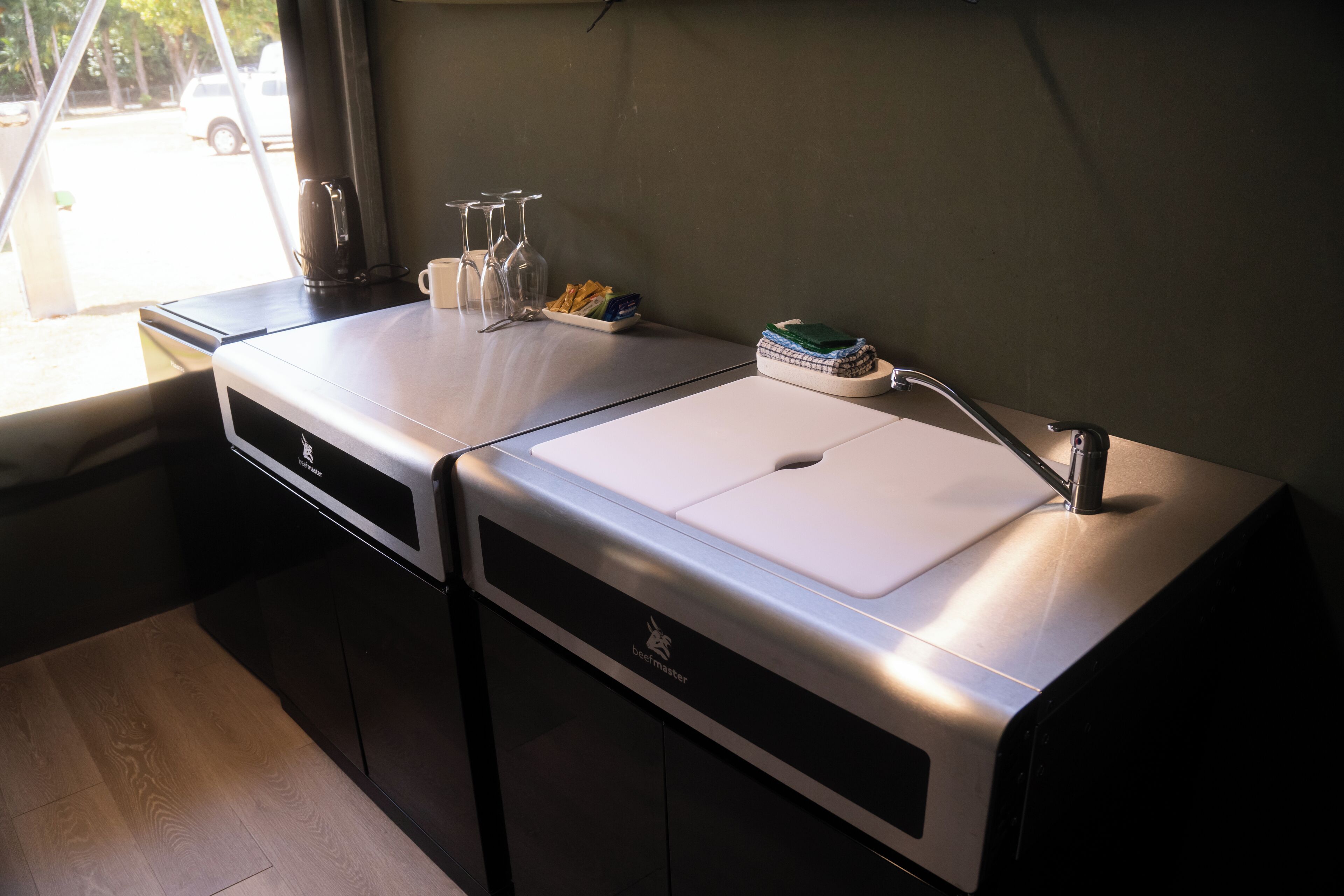 Una kitchenette equipada con estufa integrada, un lavamanos y una ventana con vista a la calle.