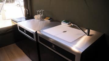 Una kitchenette equipada con estufa integrada, un lavamanos y una ventana con vista a la calle.