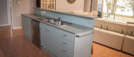 Una cocina equipada con lavavajillas, doble pileta y un reloj grande en la pared.