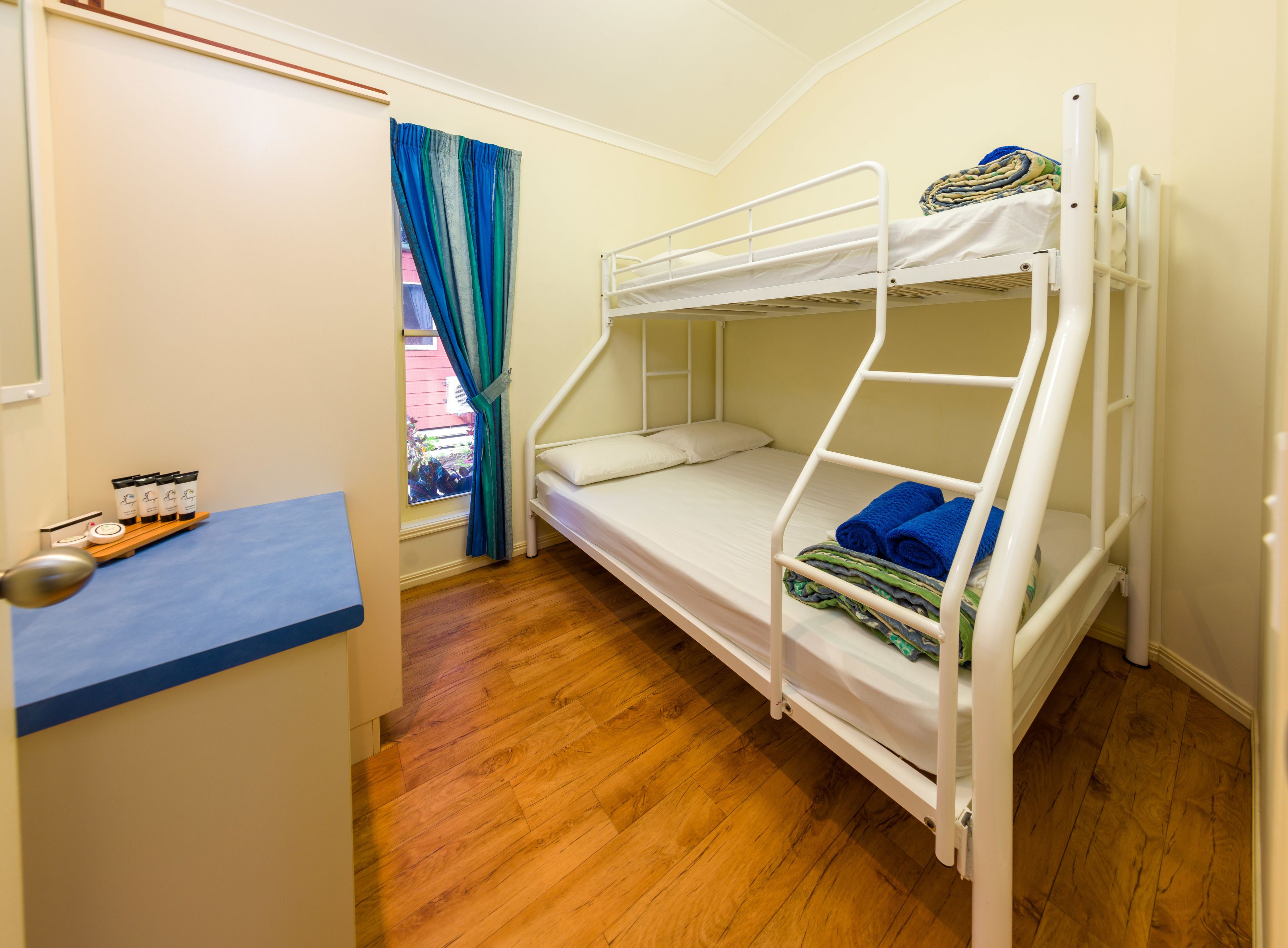 Habitación con literas, un escritorio y una ventana con cortinas.