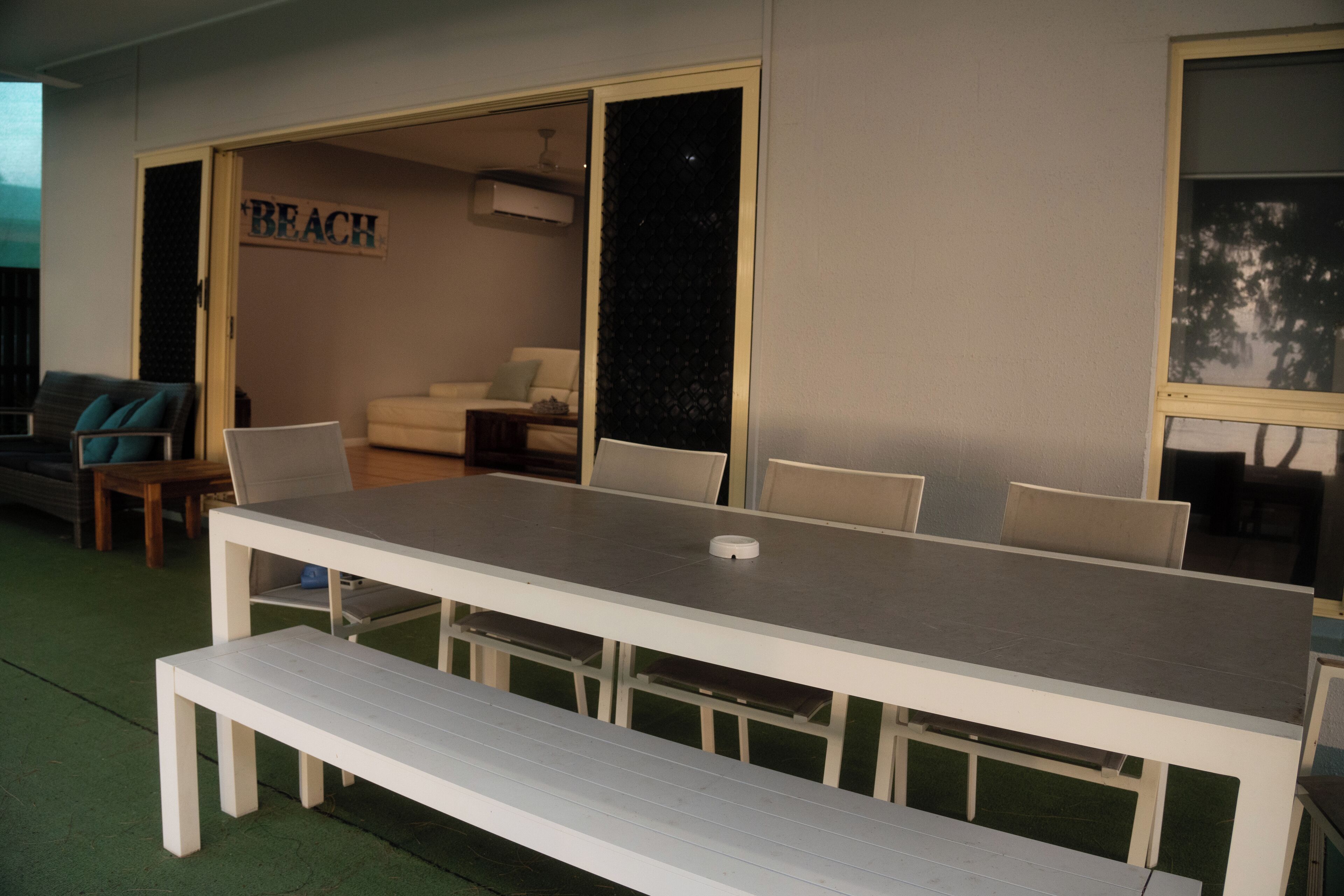 A room with a large white table and benches, a sofa, and a sign that reads "BEACH".