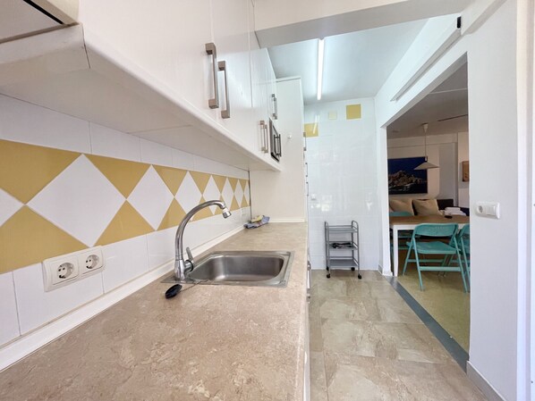 A modern kitchen with a stainless steel sink, a tiled backsplash with a geometric pattern, and a dining area with a table and chairs. - BLUE APARTMENT R022 (Benidorm)