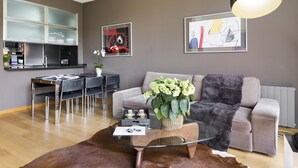 A modern living room with a sofa, coffee table, and dining area.