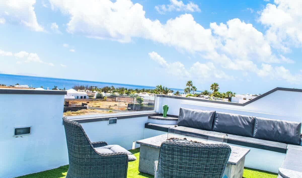 Una terrazza sul tetto con vista sul mare, arredi da esterno e un muro bianco.