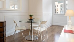Un comedor moderno con una mesa de vidrio, sillas blancas, una planta pequeña y una lámpara.