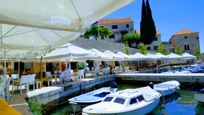 Un café situé au bord de l’eau, avec une terrasse et des bateaux amarrés à proximité.