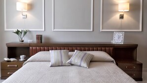 Ein ordentlich eingerichtetes Schlafzimmer mit einem Bett, Nachttischen und Wandlampen.