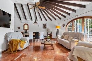 A spacious living room with a high ceiling, a dining area, and a large window with a view. - Villa Axel - PlusHolidays (Calpe)