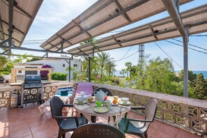 An outdoor patio with a table set for dining, surrounded by chairs, and a grill area.