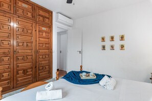 Hotelkamer met een grote houten garderobe, een bed met een blauwe deken, een klein tafeltje met een dienblad, en een wand met potplantdecoraties.