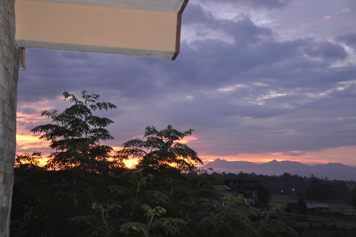 A sunset view with mountains in the background and trees in the foreground.