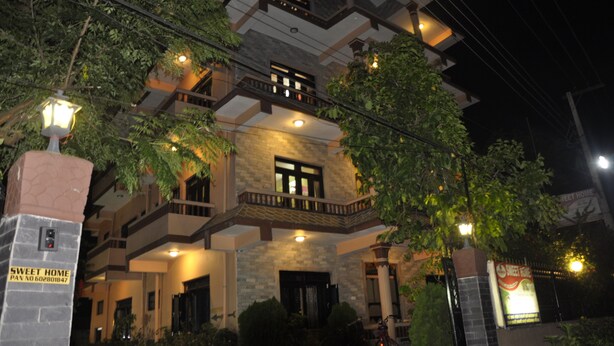 Um edifício de vários andares com varandas, fachada de pedra e uma placa com a inscrição "SWEET HOME".