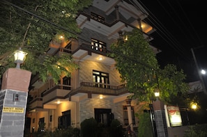 A multi-story building with balconies, a stone facade, and a sign reading "SWEET HOME." - Sweet Home (Sauraha)