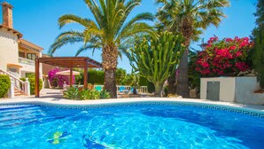 Ein Swimmingpool mit klarem, blauem Wasser, umgeben von Palmen und einer Pergola.