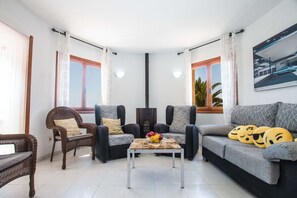 Una sala de estar con sofá, dos sillones, una mesa de centro y una chimenea.