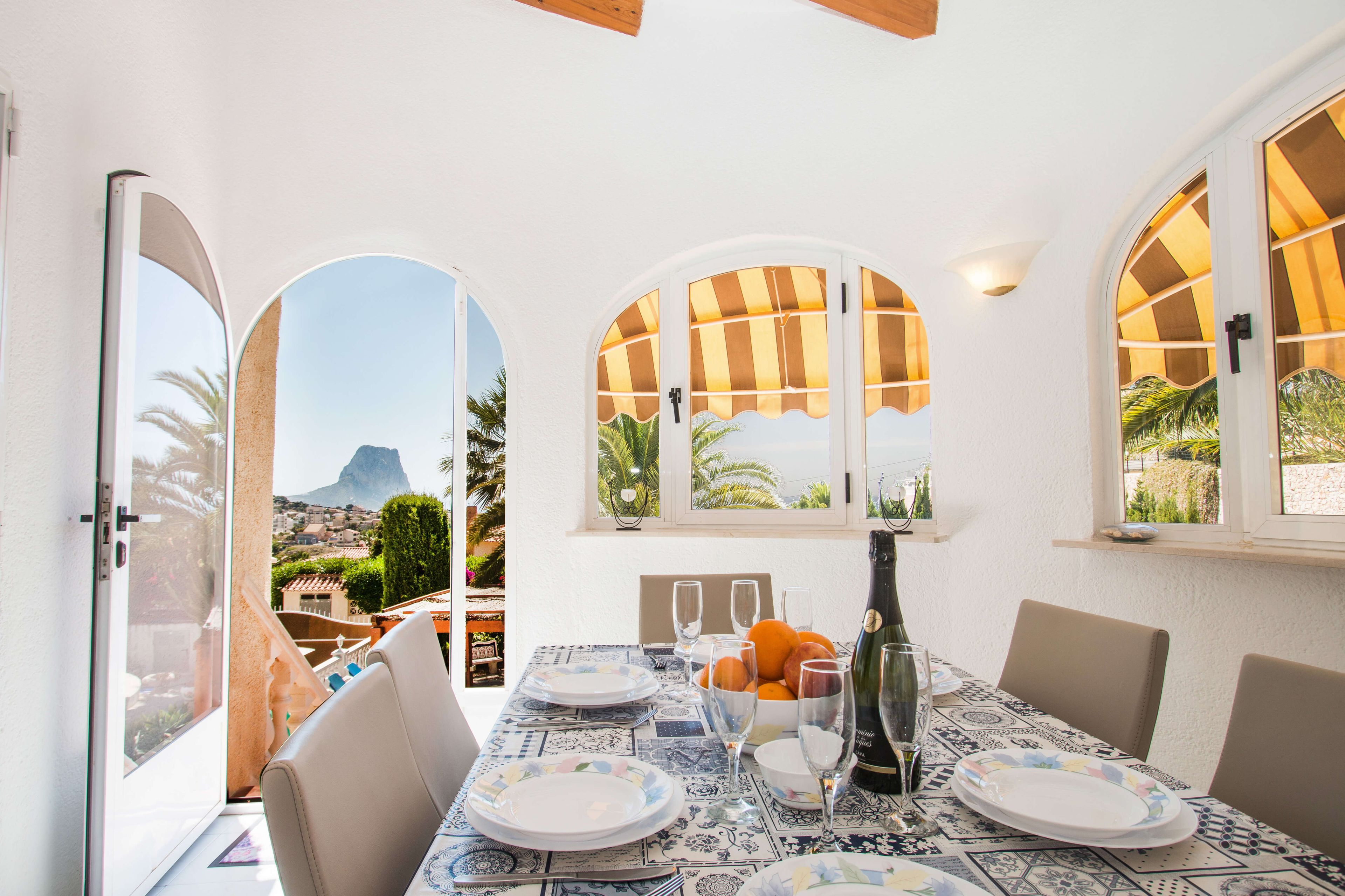 A dining area with a table set for four, overlooking a scenic view of a mountain and palm trees.