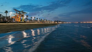 A beach with a unique sculpture and palm trees. - AirCon Apartment in front of the beach (La Pineda)
