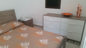 A bedroom with a bed, a bedside table with a lamp, a dresser, and a small window. - The SIRE house, historic apartment in city center (Marino)
