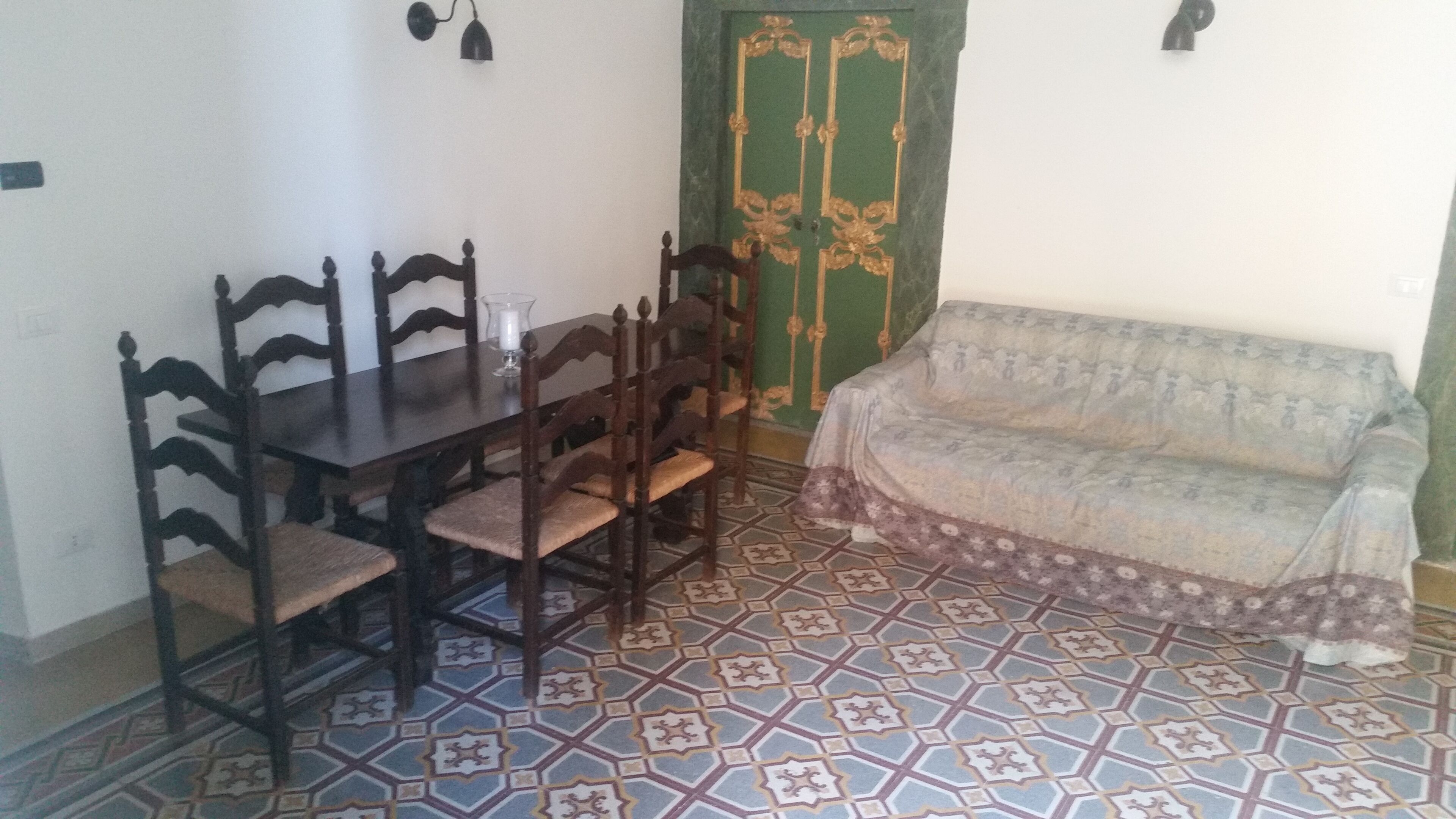 Habitació amb taula de menjador, cadires, un sofà i un sòl amb disseny.