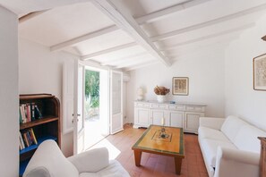 A room with a white sofa, a wooden coffee table, a bookshelf, and a white cabinet.