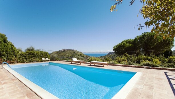 Una piscina rectangular con superficie de agua cristalina y azul, rodeada por una solana empavedada.