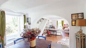 Un comedor con una mesa de madera, sillas y un jarrón de flores secas.