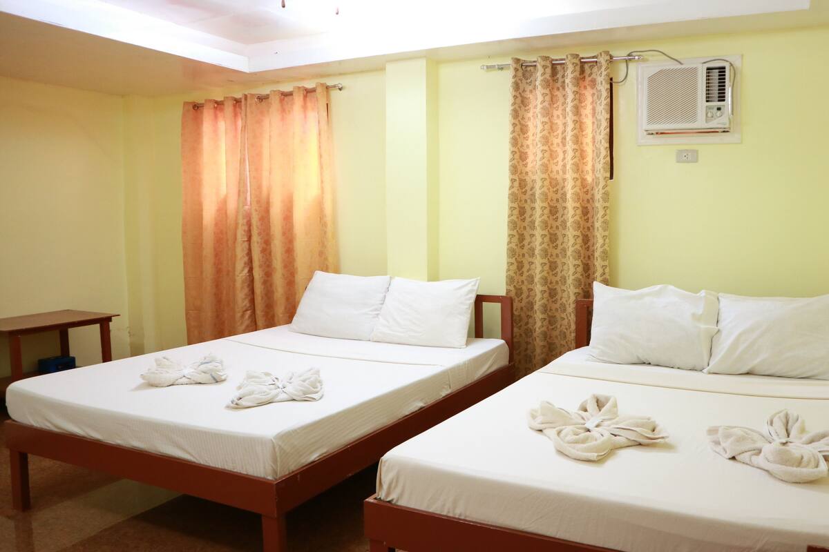 A hotel room with two beds, each with white linens and towels arranged on the beds.