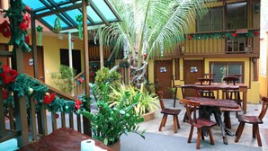 Un espace patio intérieur avec des tables et des chaises en bois, entouré de plantes en pot et de décorations de Noël.