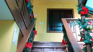 Un escalier avec des rampes en bois et un plafond en verre, décoré de guirlandes et d’ornements festifs.