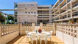 Una terrazza con tavolo e sedie, un recinto decorativo e un edificio sullo sfondo con numerosi balconi.