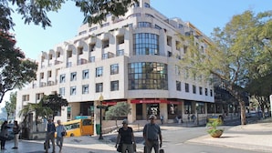 Um edifício de vários andares com fachada curva, grandes janelas e entrada no nível da rua com uma placa.