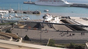Marina com navios de cruzeiro, área para pedestres e um copo de suco de laranja.
