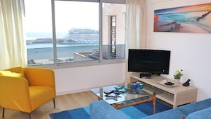 Uma sala de estar moderna com uma janela grande, uma televisão, um sofá e uma mesa de centro de vidro.