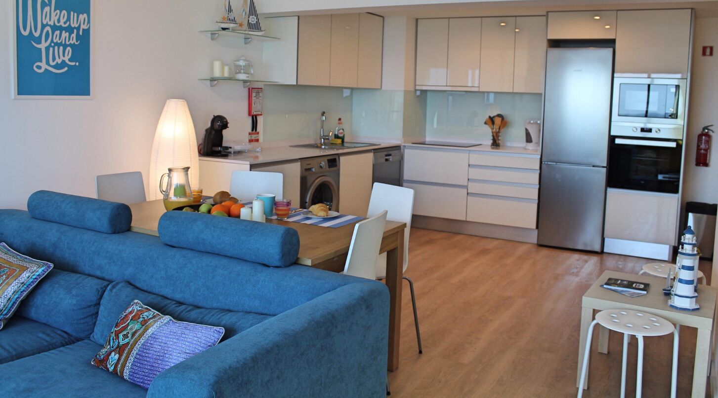 Un apartamento moderno con sala de estar, comedor, kitchenette y pequeña cocina.