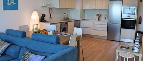 Un apartamento moderno con sala de estar, comedor, kitchenette y pequeña cocina.