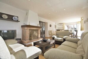 A living room with a fireplace, sofas, a coffee table, and a television. - Villa Calalga - PlusHolidays (Calpe)