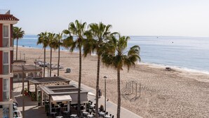 Un hôtel situé en bord de mer, doté d’une terrasse et bordé de palmiers.