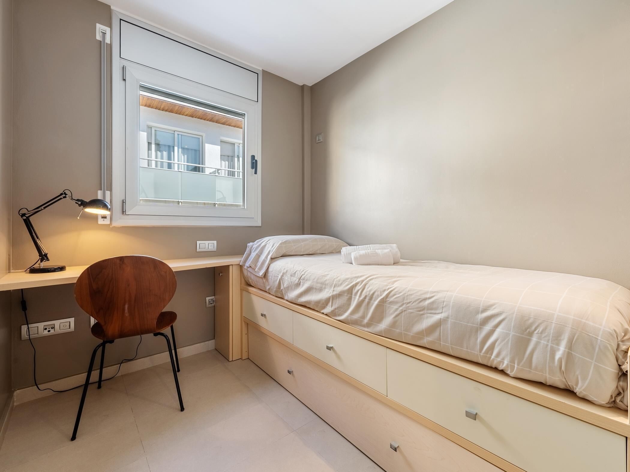 Een slaapkamer met een bed, een bureau en een stoel.