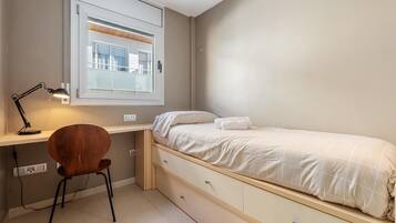 Een slaapkamer met een bed, een bureau en een stoel.