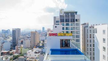 A modern hotel with a rooftop pool, surrounded by urban buildings.