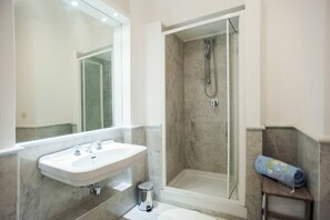 Une salle de bain équipée d’un lavabo, d’un miroir, d’une douche et d’un porte-serviettes.