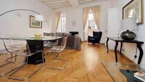 A spacious living area with a wooden floor, a round glass table, modern chairs, a sofa, and a black armchair. - Rome, near Piazza di Spagna, modern and spacious apartment for 8 (Roma)