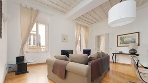 A spacious living room with a sofa, a TV, a lamp, and a window with curtains. - Rome, near Piazza di Spagna, modern and spacious apartment for 8 (Roma)
