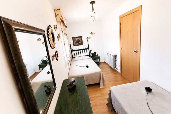 Une chambre à coucher avec un lit, des tables de chevet, un miroir, une commode et une porte.