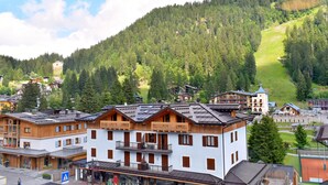 A multi-story hotel with balconies, a ski resort in the background, and a mountainous landscape. - EMERALD 37 STUDIO 022143-AT-672308 (Madonna di Campiglio)