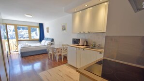 A modern hotel room with a bed, a dining table, and a kitchenette. - EMERALD 37 STUDIO 022143-AT-672308 (Madonna di Campiglio)